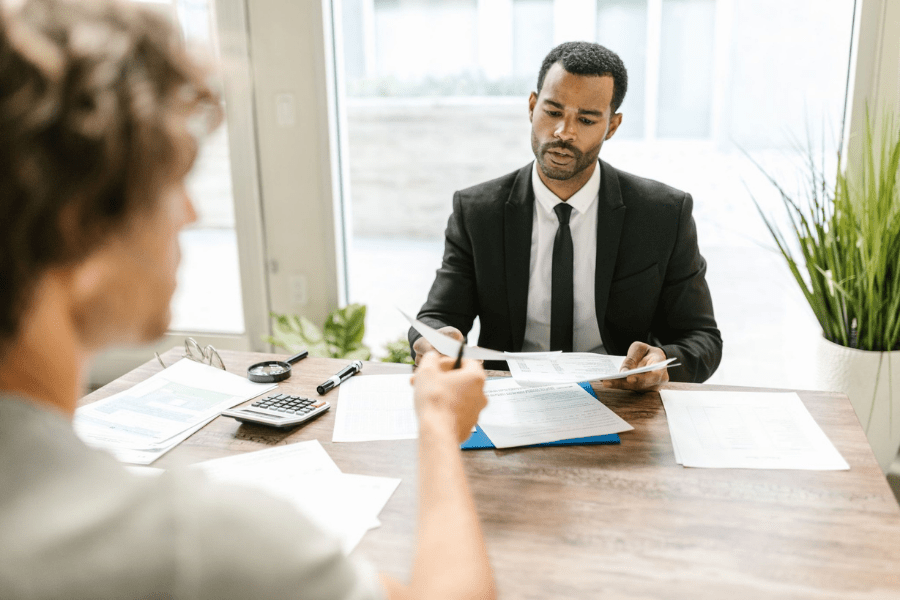 Financial advisor or actuary reviewing retirement plan paperwork with a physician or practice owner across a desk