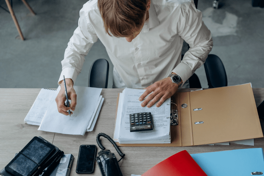 Older professional or business owner reviewing retirement account statements with a calculator on the desk