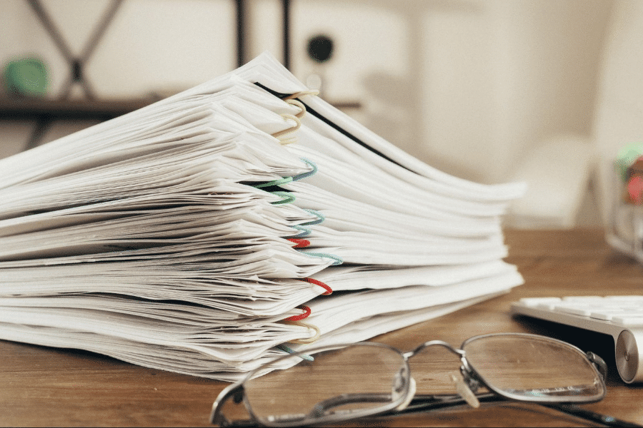 Stack of paperwork and reading glasses on a desk, representing the documents behind an asset protection plan.