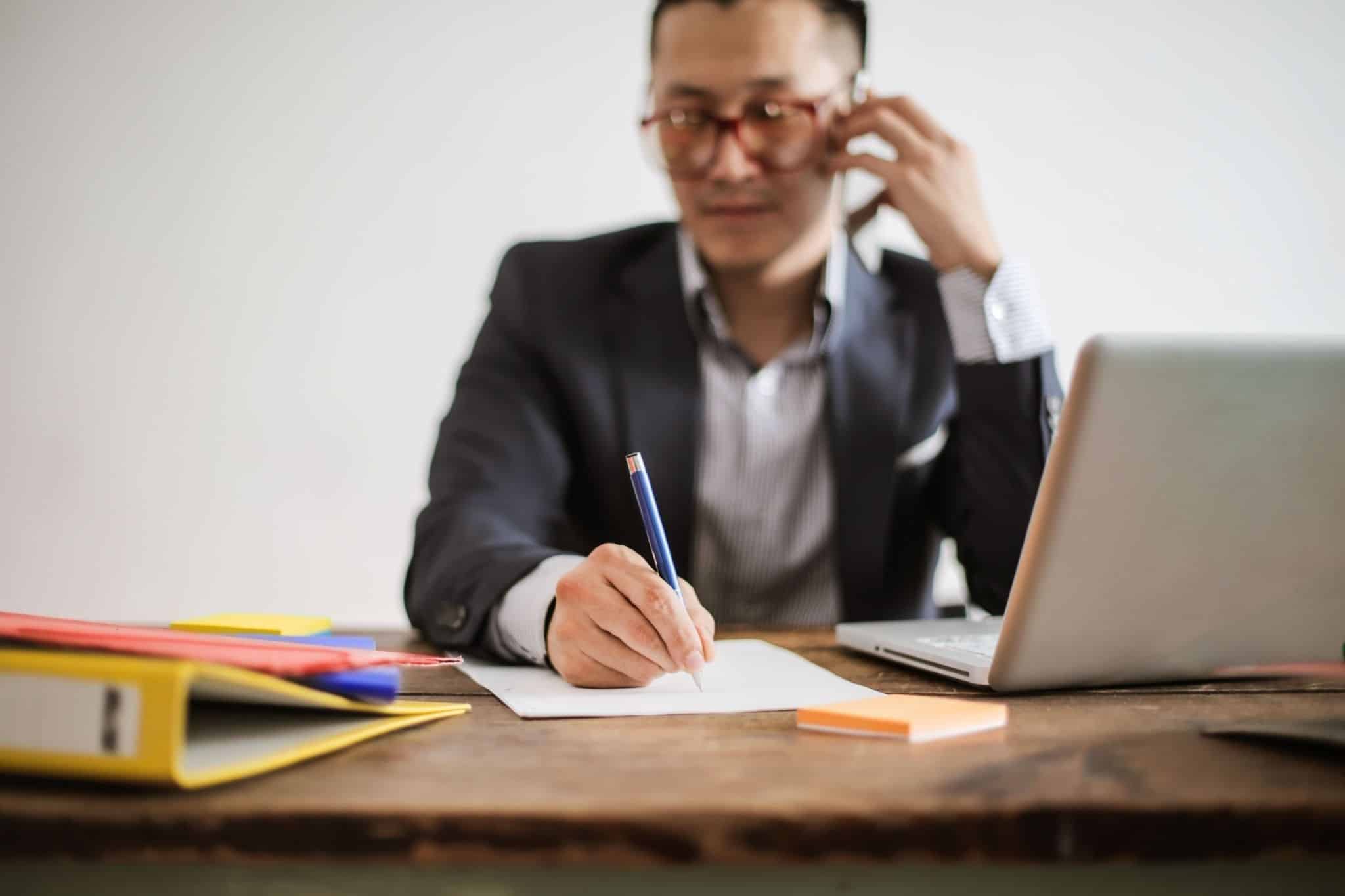 Business owner multitasking on the phone while reviewing documents, representing the demands of running a business