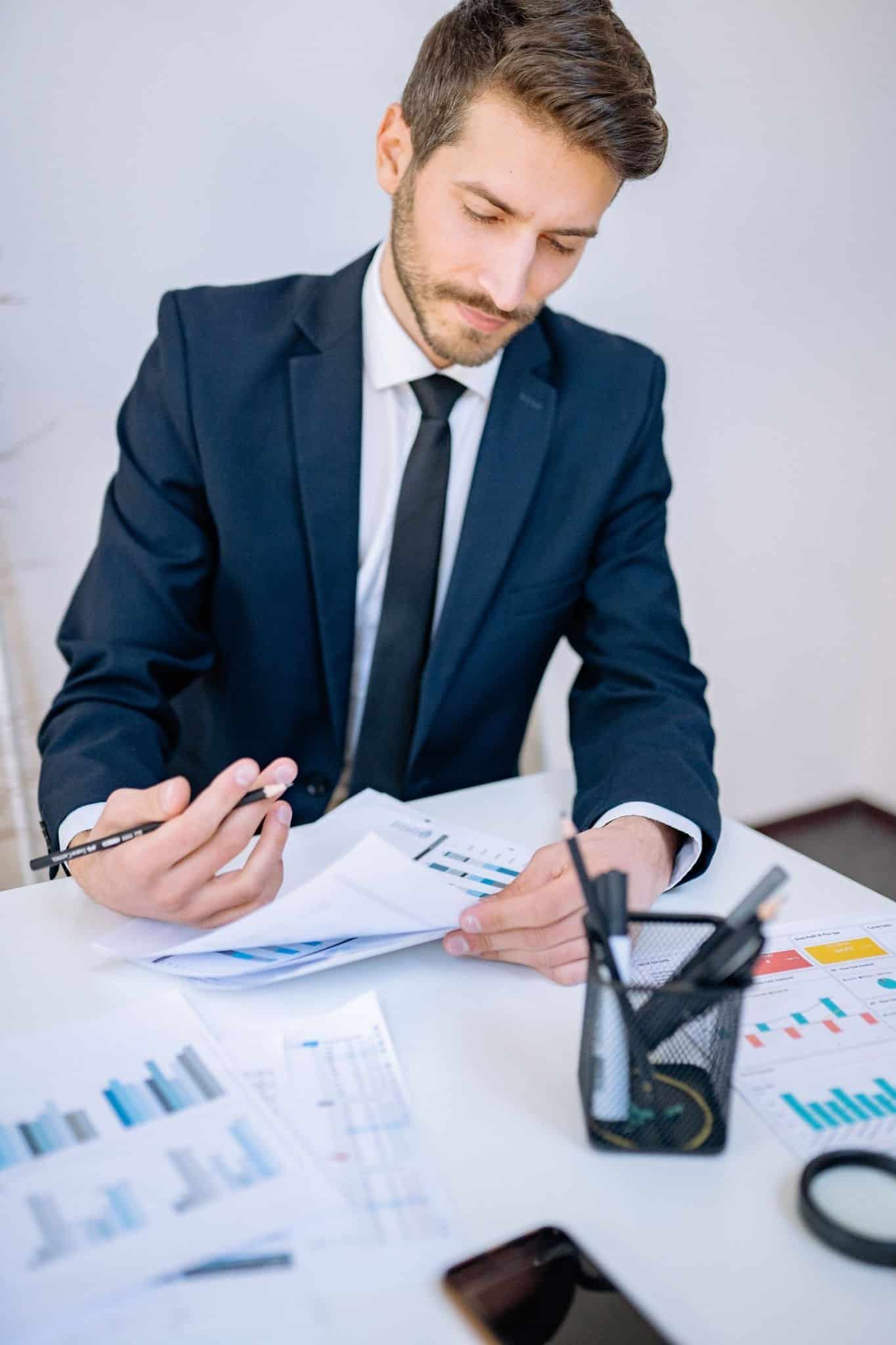 Business owner reviewing financial charts and reports at his desk during a mid-year tax checkup