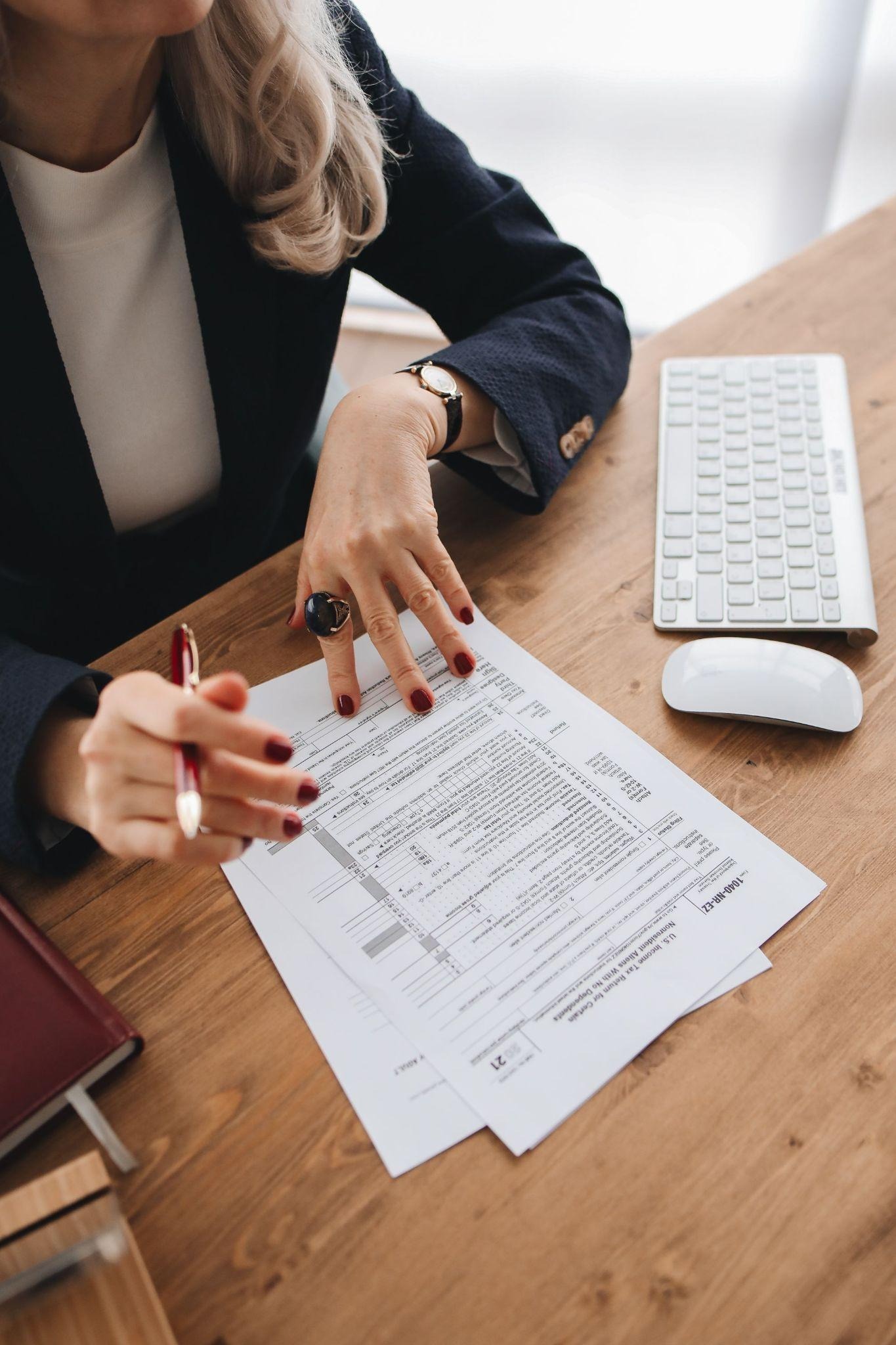 Advisor in a dark blazer reviewing a printed tax return while holding a red pen
