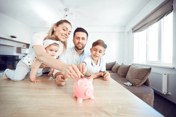 Family putting money into a piggy bank representing cutting down and shifting income