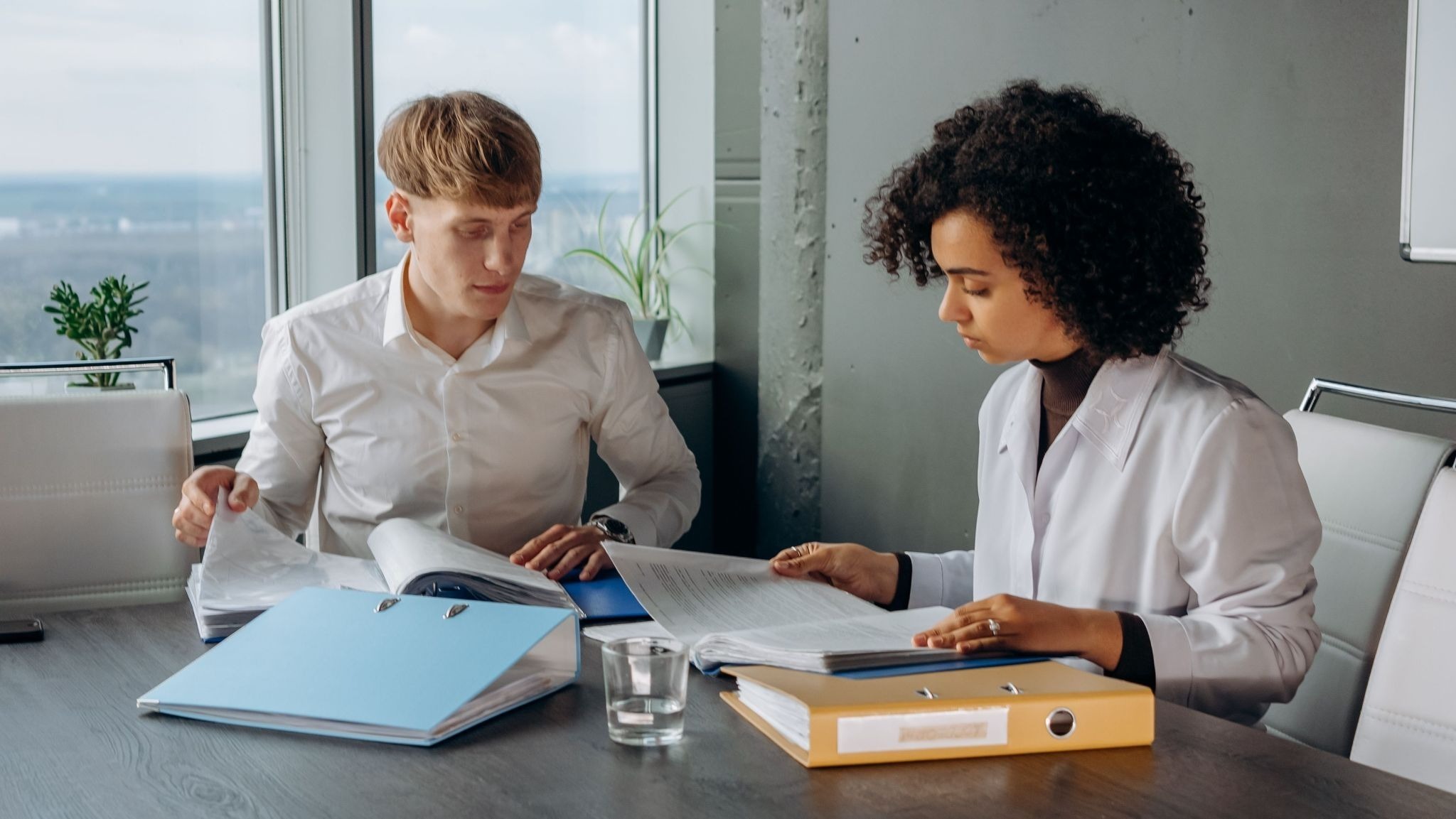 Two physicians reviewing liability paperwork together in a clinic office