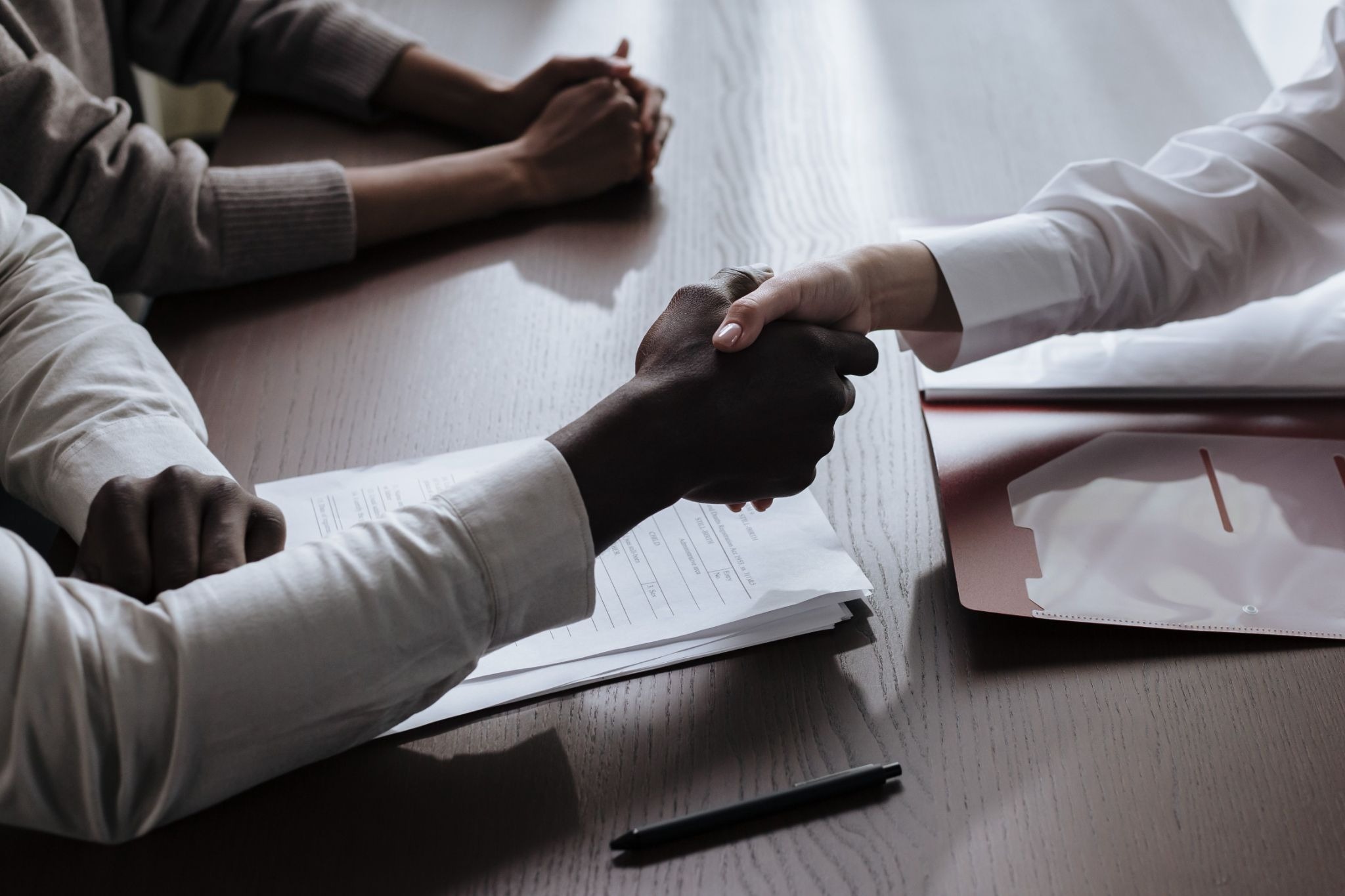 Physician shaking hands with an advisor across a desk